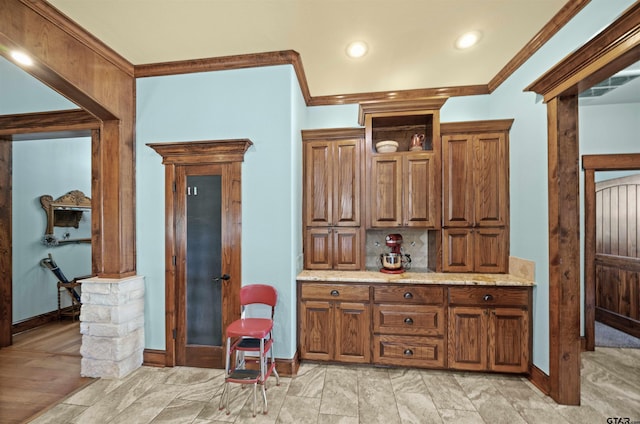 kitchen featuring light wood-type flooring, light stone counters, and crown molding