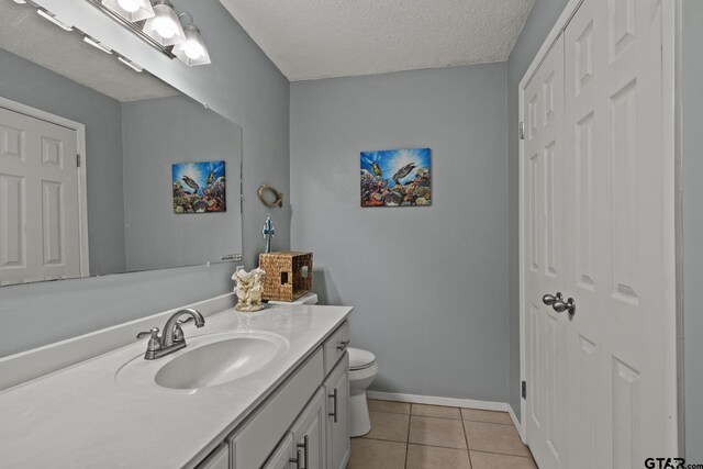 bathroom featuring tile patterned floors, vanity, a textured ceiling, toilet, and curtained shower