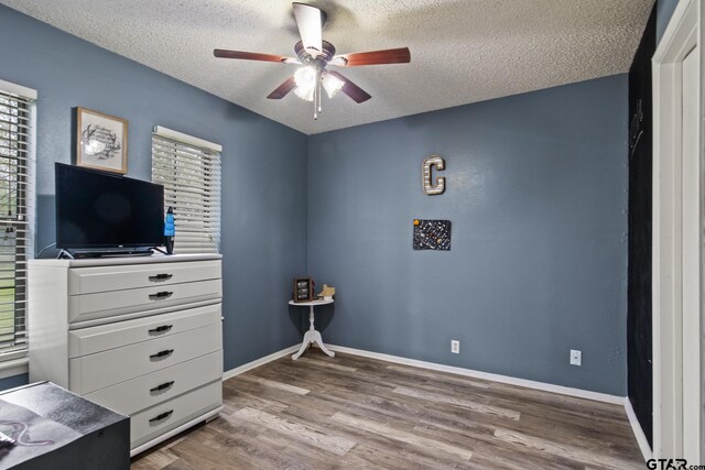 bedroom with hardwood / wood-style floors, a textured ceiling, and ceiling fan