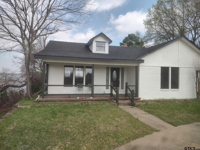 view of front of home featuring brick siding, a porch, a front yard, and a shingled roof