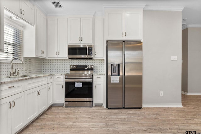 kitchen with light stone counters, sink, white cabinets, and appliances with stainless steel finishes