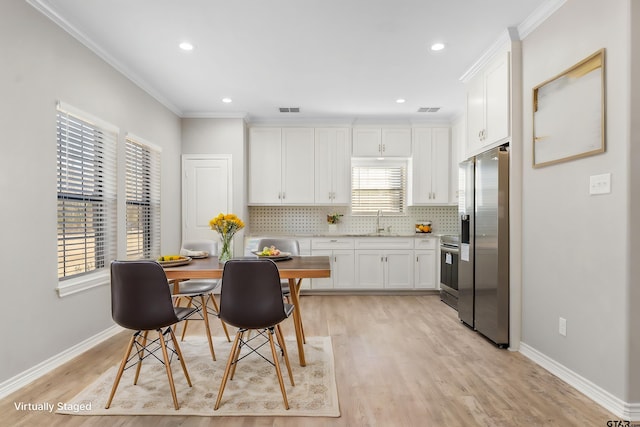 kitchen with sink, appliances with stainless steel finishes, white cabinetry, ornamental molding, and light wood-type flooring