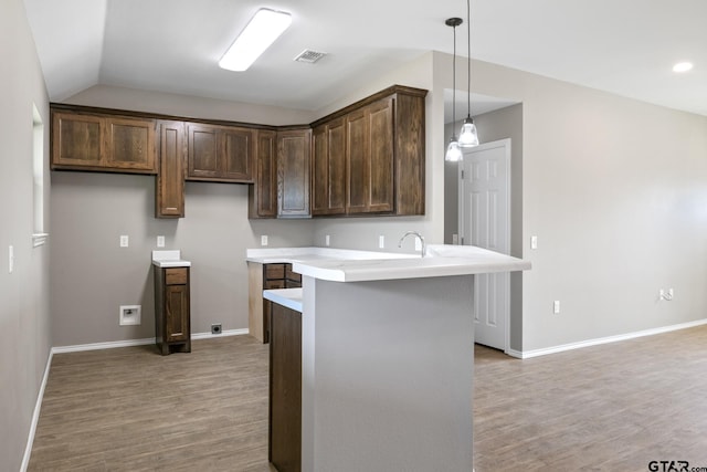 kitchen featuring light wood-style floors, a peninsula, light countertops, baseboards, and lofted ceiling