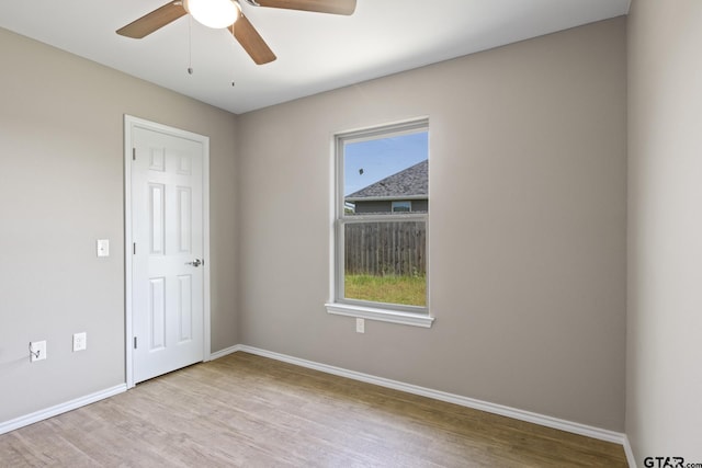 unfurnished room with wood finished floors, ceiling fan, plenty of natural light, and baseboards