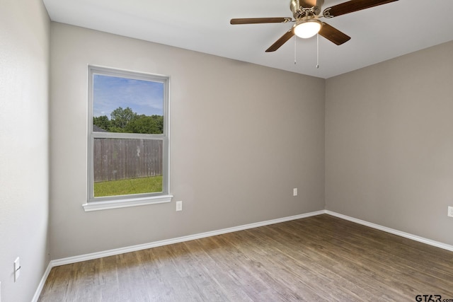 empty room featuring wood finished floors, baseboards, and ceiling fan