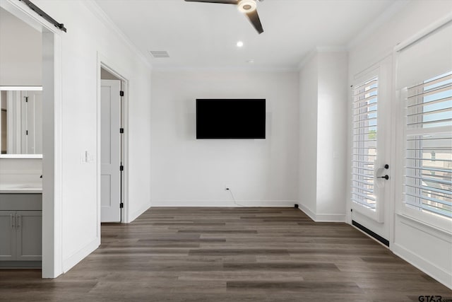 unfurnished living room with dark wood-type flooring, a barn door, a healthy amount of sunlight, and crown molding