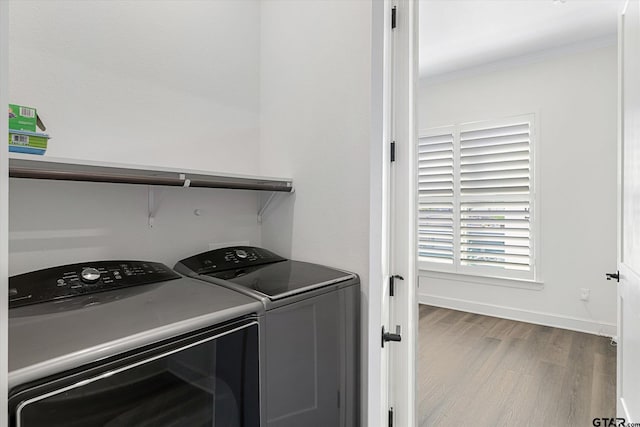 laundry area featuring separate washer and dryer, hardwood / wood-style floors, and crown molding