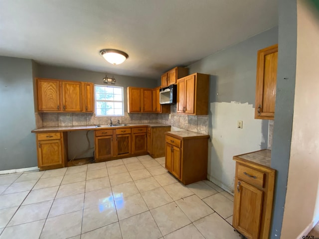 kitchen featuring decorative backsplash, light tile patterned floors, and sink