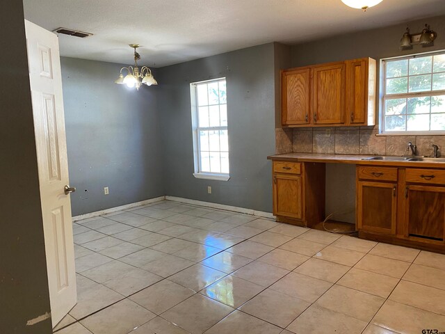 kitchen with sink, an inviting chandelier, tasteful backsplash, decorative light fixtures, and light tile patterned flooring