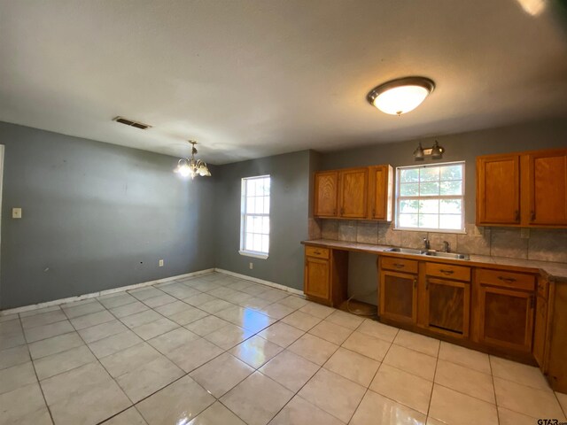 kitchen with tasteful backsplash, a wealth of natural light, sink, and a notable chandelier