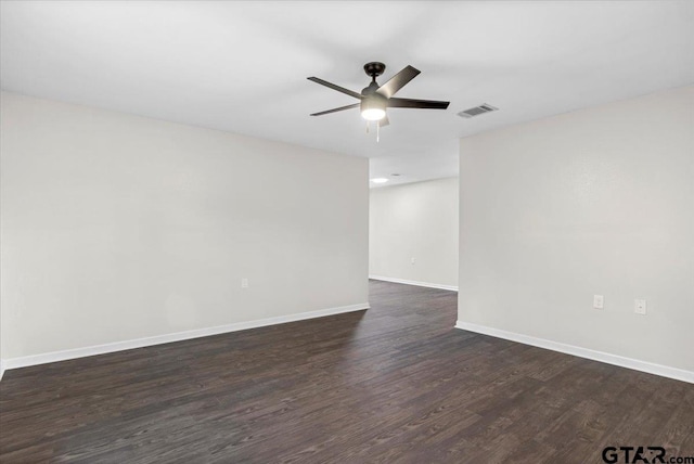 empty room with dark wood-style flooring, baseboards, a ceiling fan, and visible vents