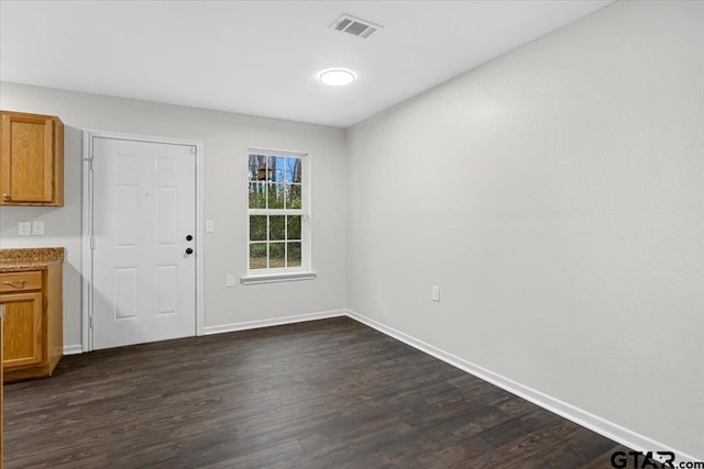 unfurnished dining area with visible vents, baseboards, and dark wood finished floors