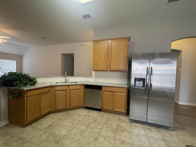 kitchen featuring light stone counters, visible vents, a peninsula, a sink, and stainless steel appliances