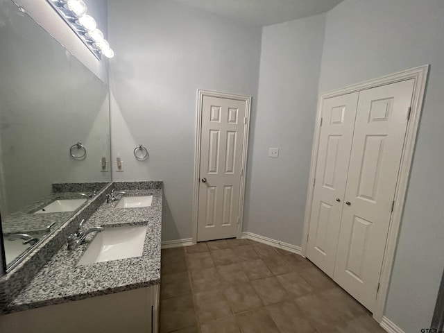 full bathroom featuring a sink, baseboards, and double vanity