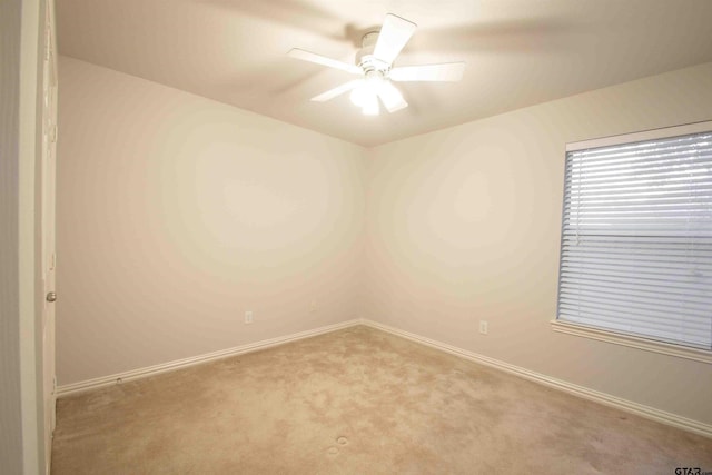 carpeted empty room featuring baseboards and a ceiling fan