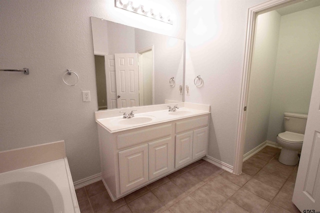 full bath with a sink, baseboards, toilet, and double vanity