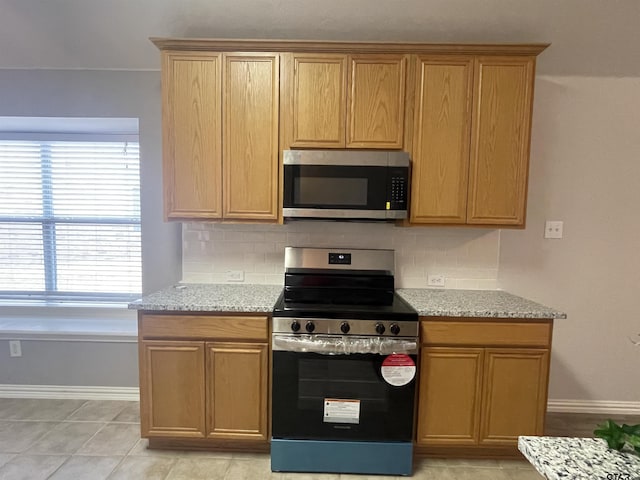 kitchen with light stone counters, tasteful backsplash, and stainless steel appliances