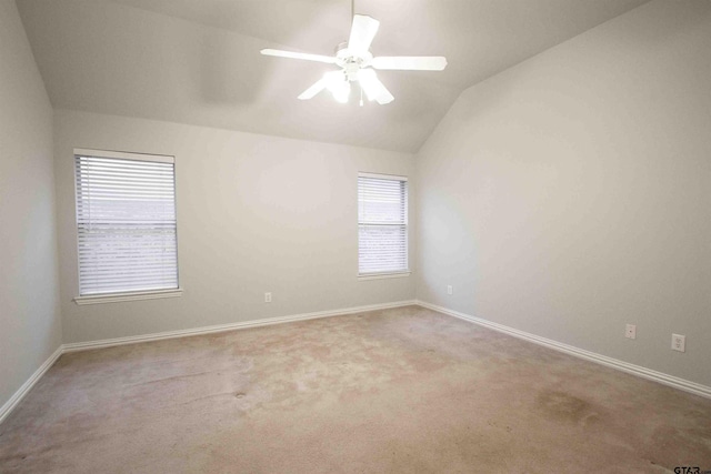 empty room with vaulted ceiling, a ceiling fan, baseboards, and carpet floors