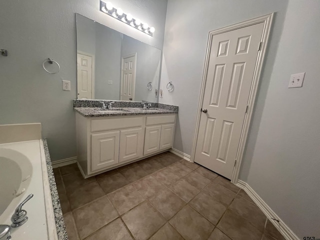 bathroom with double vanity, tile patterned flooring, a garden tub, and a sink