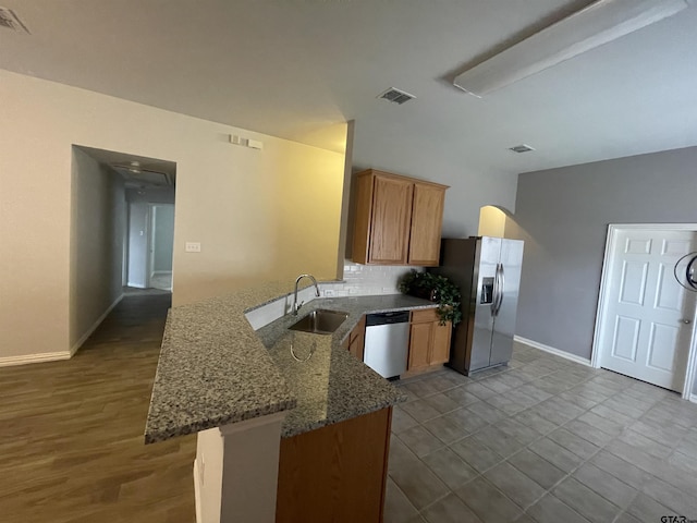 kitchen with visible vents, a sink, stainless steel appliances, a peninsula, and stone counters