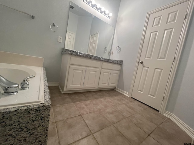 full bath featuring tile patterned floors, baseboards, a tub to relax in, and double vanity