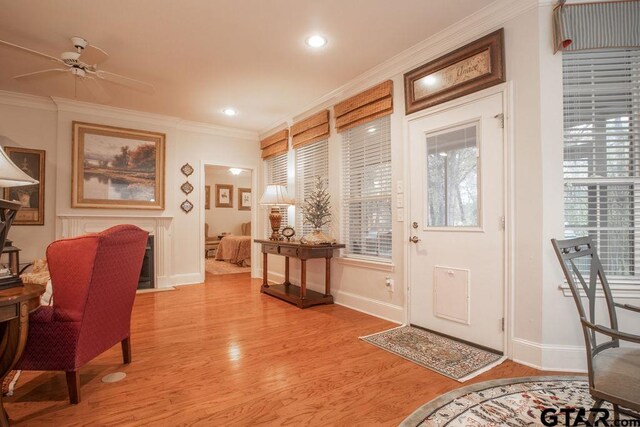 foyer featuring ceiling fan, ornamental molding, and light wood-type flooring