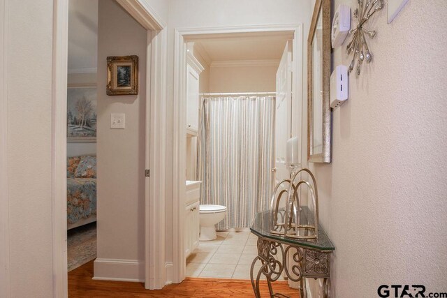 bathroom with crown molding, toilet, and hardwood / wood-style flooring