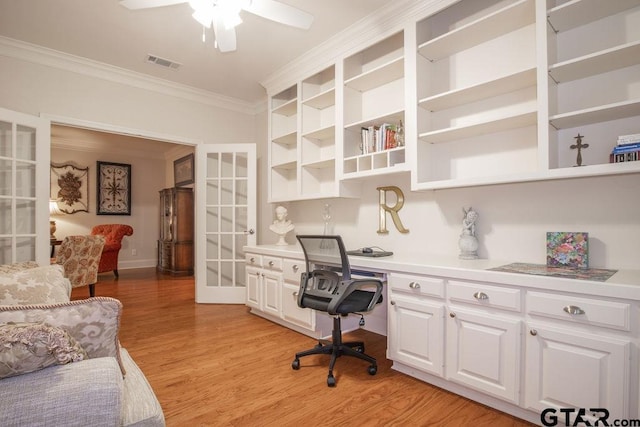 home office with crown molding, ceiling fan, built in desk, and light wood-type flooring