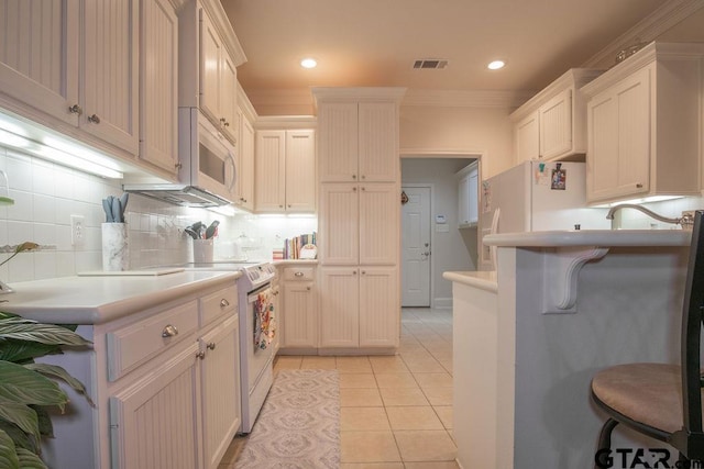 kitchen with range, crown molding, light tile patterned floors, white fridge, and white cabinetry