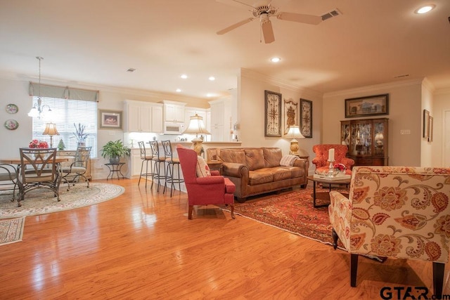 living room with crown molding, light hardwood / wood-style flooring, and ceiling fan