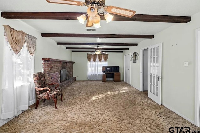 living room with beamed ceiling, ceiling fan, a fireplace, and carpet