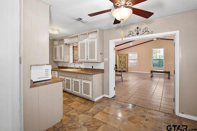 kitchen featuring lofted ceiling, sink, white cabinets, and ceiling fan