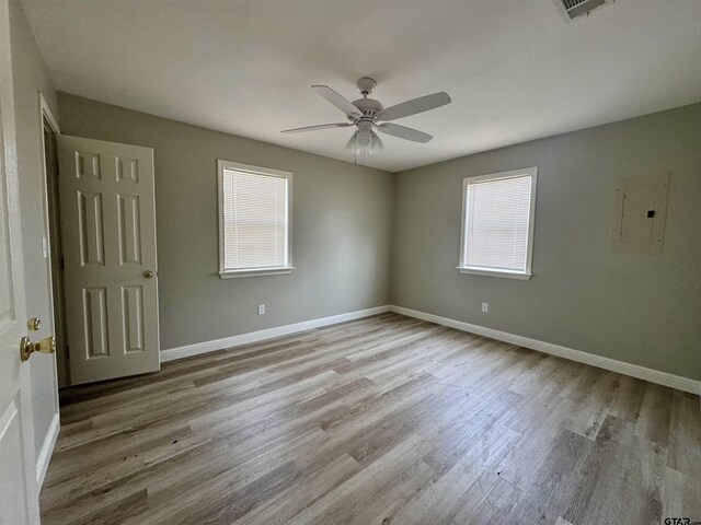 spare room featuring electric panel, ceiling fan, and light wood-type flooring