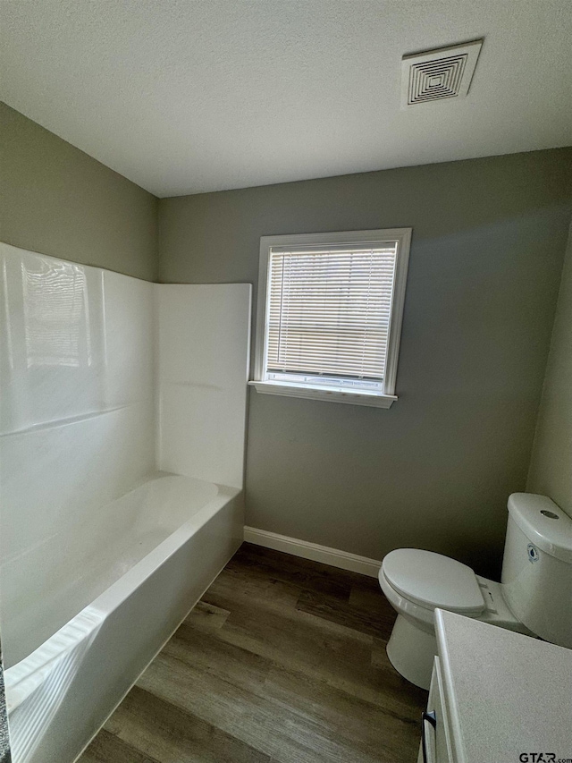 bathroom with wood-type flooring, vanity, a textured ceiling, and toilet