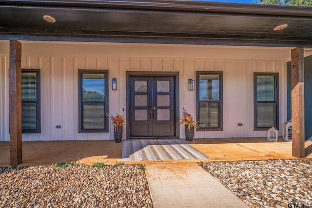 view of exterior entry featuring covered porch and french doors