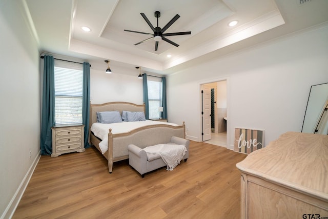 bedroom featuring a tray ceiling, light hardwood / wood-style flooring, and multiple windows