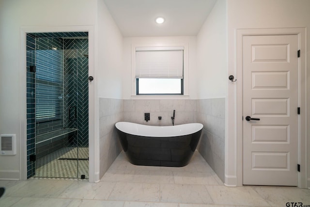 bathroom featuring independent shower and bath and tile walls