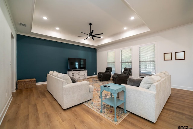 living room with hardwood / wood-style floors, a raised ceiling, and ceiling fan