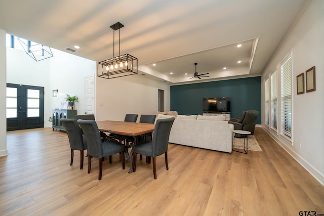 dining room with ceiling fan, plenty of natural light, light wood-type flooring, and a tray ceiling