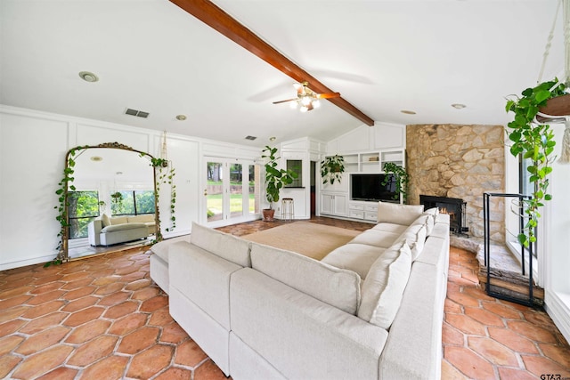 living room featuring lofted ceiling with beams, ceiling fan, a stone fireplace, and built in features