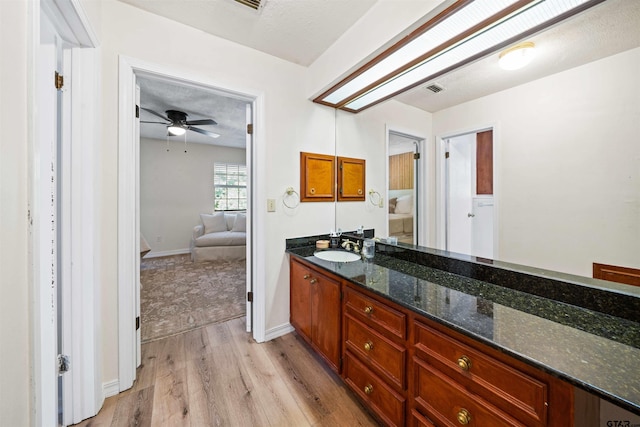 bathroom featuring ceiling fan, hardwood / wood-style floors, vanity, and a textured ceiling