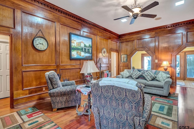 living room featuring ceiling fan, arched walkways, light wood-style flooring, and a decorative wall