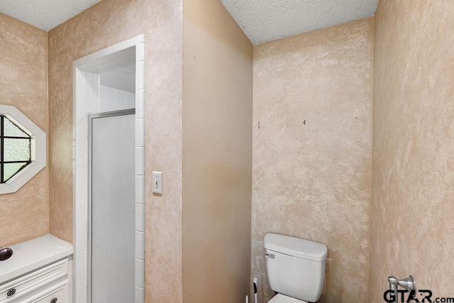 bathroom with toilet, a textured ceiling, and a shower