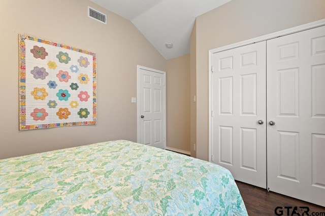 bedroom featuring dark hardwood / wood-style floors, vaulted ceiling, and a closet