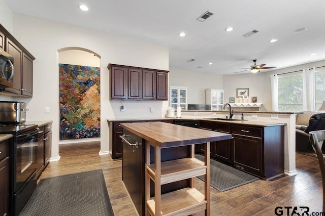 kitchen with wooden counters, dark wood-type flooring, kitchen peninsula, black / electric stove, and sink