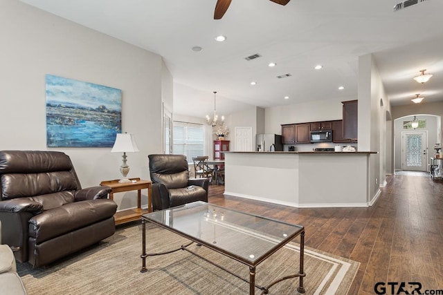 living room with dark wood-type flooring, ceiling fan with notable chandelier, and vaulted ceiling