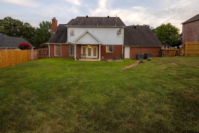 back of house featuring cooling unit, a patio area, and a lawn