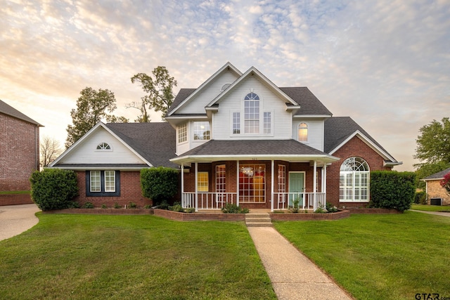 view of front of property featuring covered porch and a yard