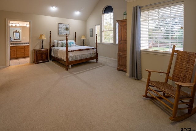 carpeted bedroom with ensuite bath, multiple windows, and vaulted ceiling