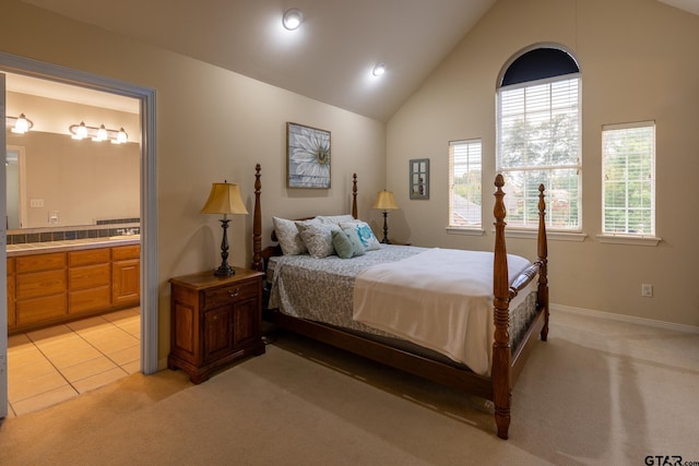 carpeted bedroom featuring ensuite bath and lofted ceiling